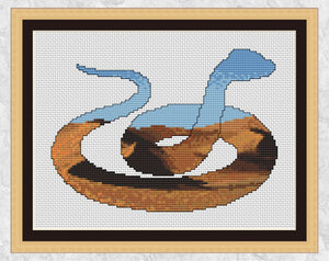 Cross stitch pattern PDF of the silhouette of a snake, filled with a desert of shifting dunes. Shown with frame.