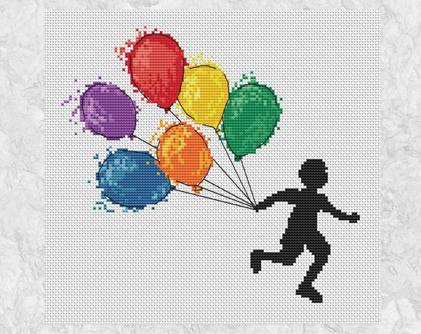 Cross stitch pattern of a boy running with watercolour effect balloons in rainbow colours. Shown without frame.