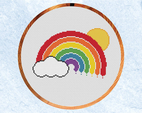 Cross stitch pattern of a rainbow, cloud and sun. Shown in hoop