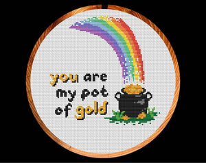 Cross stitch pattern of a rainbow falling on a pot of gold, with the words 'you are my pot of gold'. Shown in hoop.