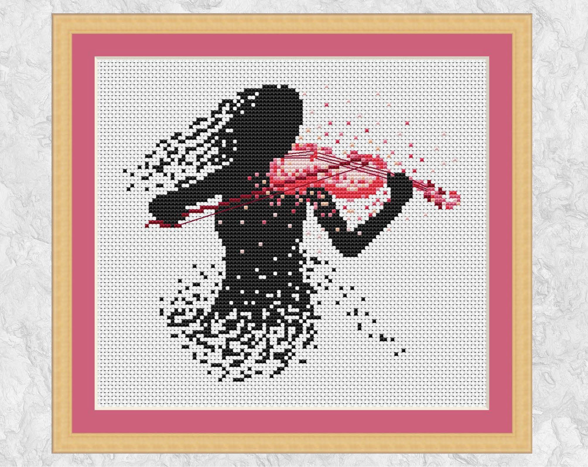 Modern art cross stitch pattern of a female violin player. Shown with frame.
