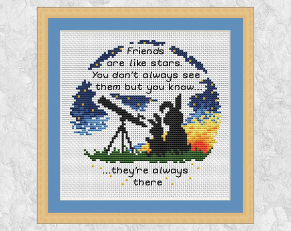 Cross stitch pattern of two bunnies looking through a telescope, with the words 'Friends are like stars. You don't always see them but you know they're always there." Shown in frame.