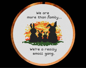 Cross stitch pattern of four bunny silhouettes against a sunset, with the words "We are more than family... We're a really small gang.". Shown in hoop.