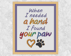 Cross stitch pattern of the words "When I needed a hand I found your paw", with a heart and paw print. Shown with frame.