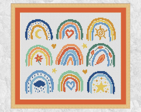 Cross stitch pattern of nine mini boho rainbows. Spring, summer, autumn and winter are all represented along with the stars and the moon. Shown with frame and orange mount.