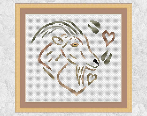 Cross stitch pattern of a goat, hearts and hoof prints, all forming a heart. Shown with frame.