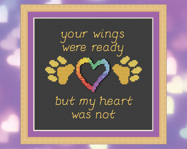 Pet memorial cross stitch pattern of the words 'Your wings were ready, but my heart was not', with paw prints and hearts. Shown with frame.