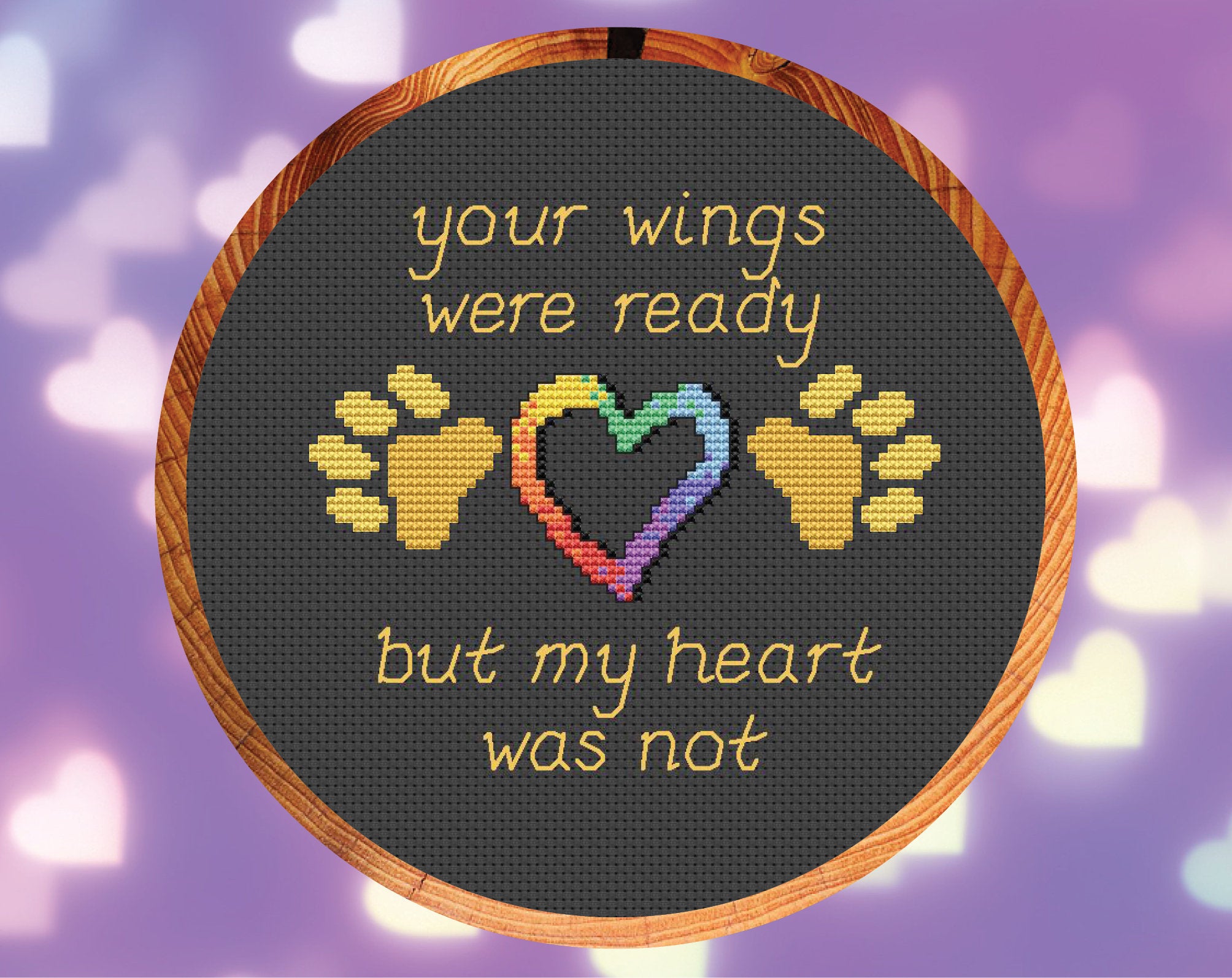 Pet memorial cross stitch pattern of the words 'Your wings were ready, but my heart was not', with paw prints and hearts. Shown in hoop.