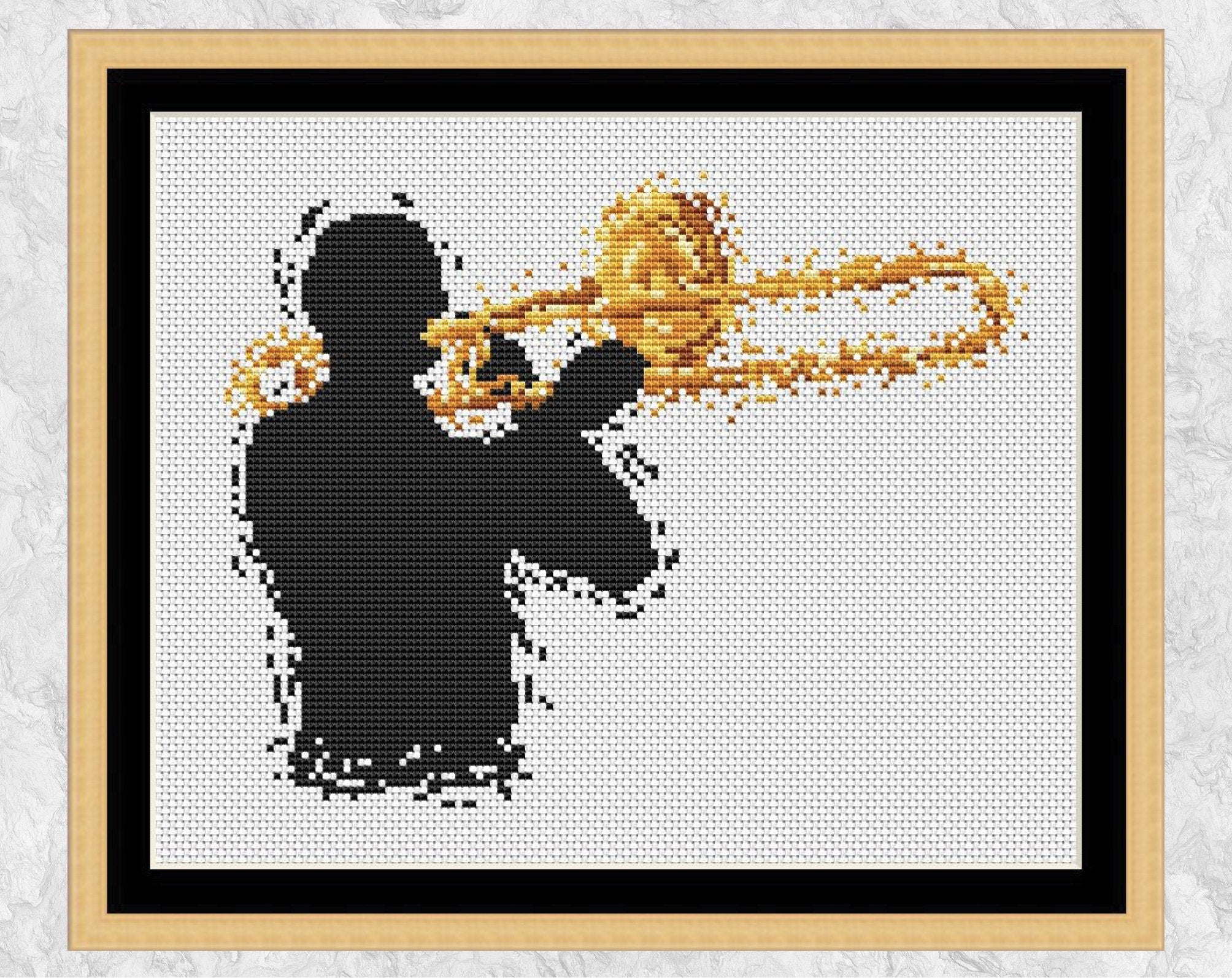 Modern art cross stitch pattern of a male trombonist. Shown with frame.