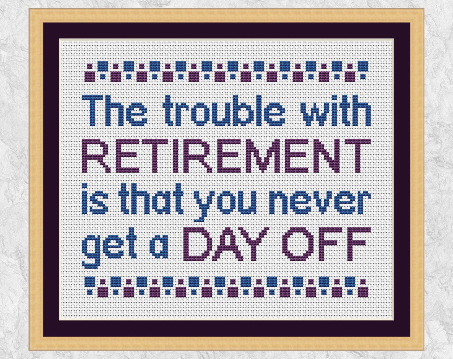 Cross stitch pattern of the quote ‘The trouble with retirement is that you never get a day off’. Shown with frame.