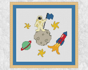 Space Adventures cross stitch pattern - cartoon astronaut on tiny moon surrounded by stars, planet and rocket - shown with frame